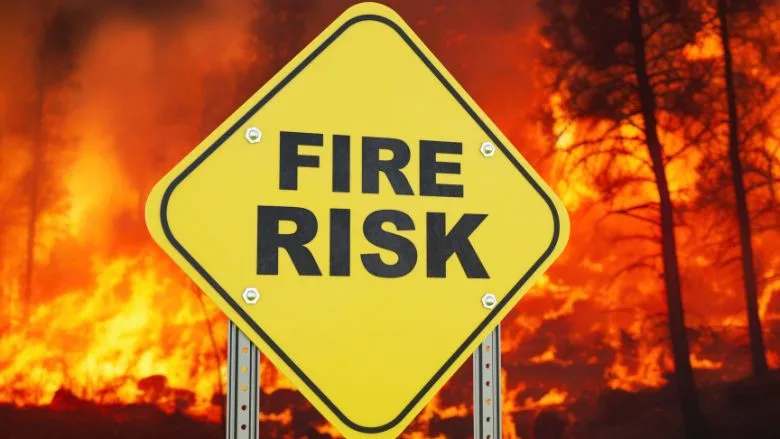 Fire risk sign with a bush fire in background
