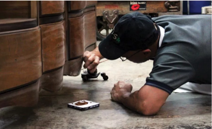 An experienced restorer repairing the water-damaged base of a piece of furniture.