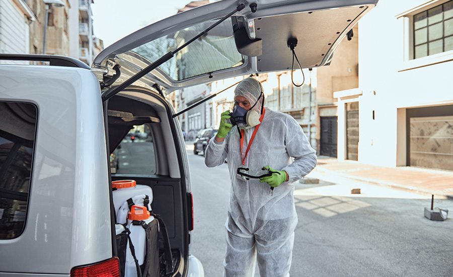 man in ppe standing behind a van