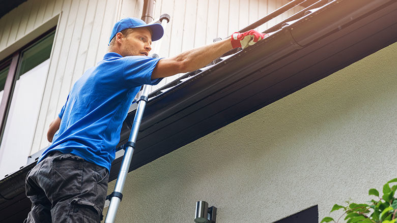 using a stepladder to clean an eave