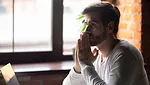 Concerned man sitting near laptop and thinking