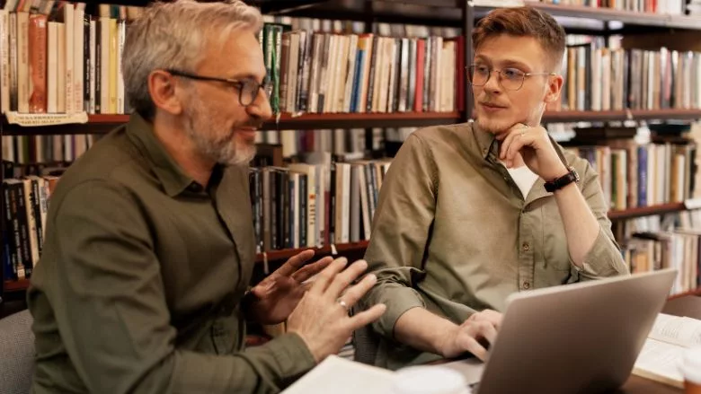 College Students Working in Library Being Helped by Tutor