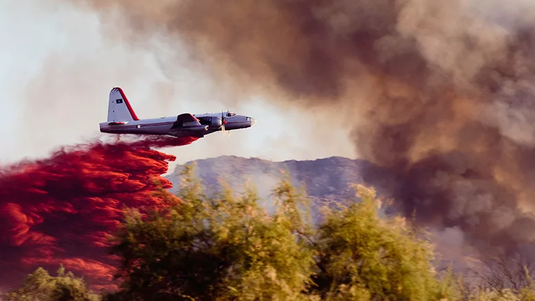 Wildfire air tanker dropping red fire retardant