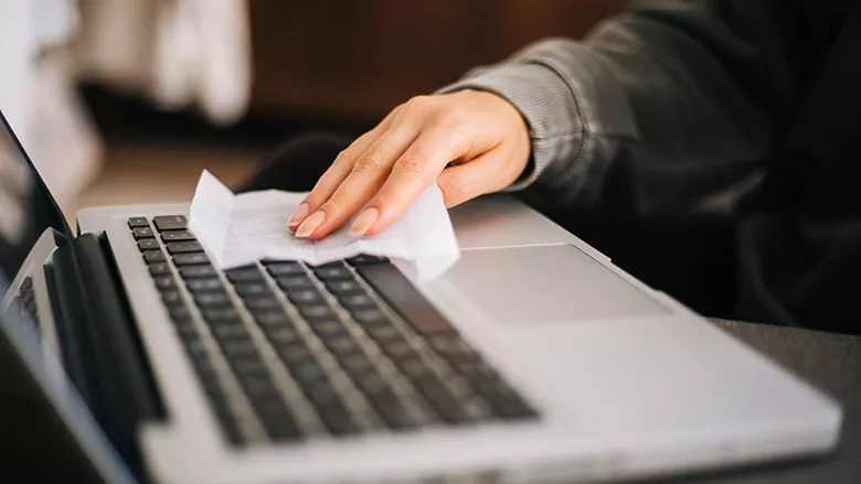 Hand wiping down surfaces on keyboard