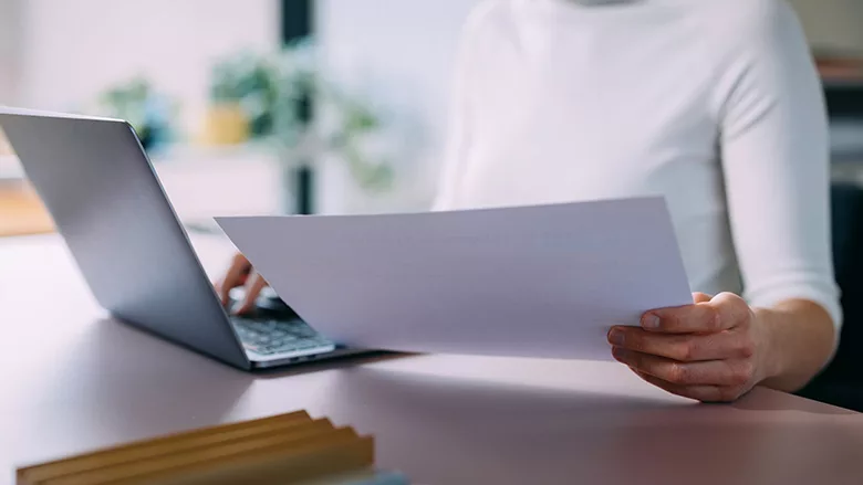 Woman Working on Laptop While Reviewing Documents