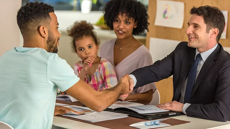 Man and his family shaking hands with a male salesperson