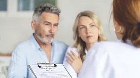 Doctor filling out medical insurance form with mature couple