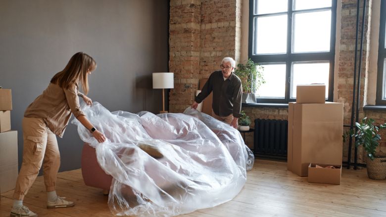 man helping his daughter cover sofa with plastic film
