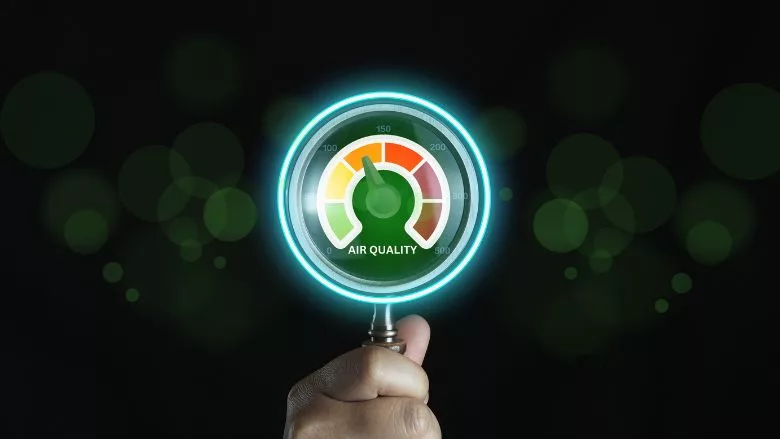 Hand holding a magnifying glass with air quality meter