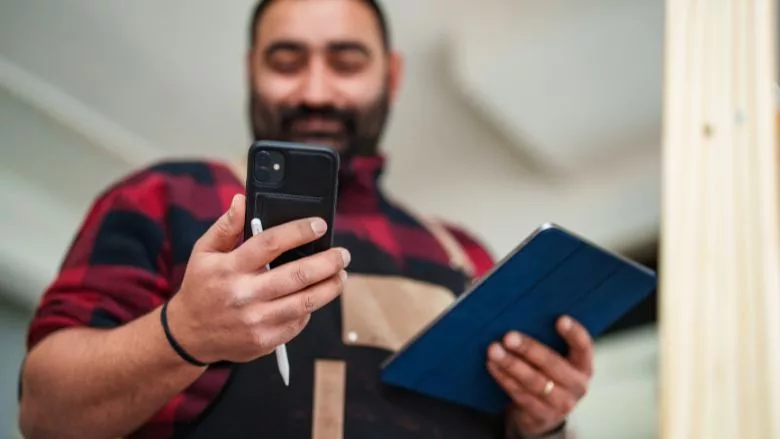 Shop owner using mobile phone and digital tablet