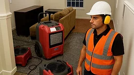 Contractor with hearing protection on jobsite with air movers