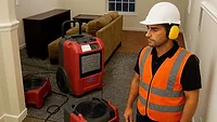 Contractor with hearing protection on jobsite with air movers