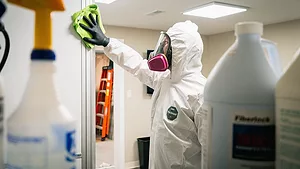 restoration technician in full PPE cleaning Containment