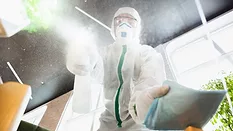 A disinfector in a protective suit and mask sprays disinfectants in the house or office 