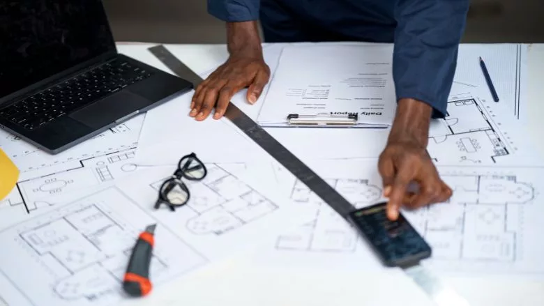 construction worker using smartphone over architectural plans