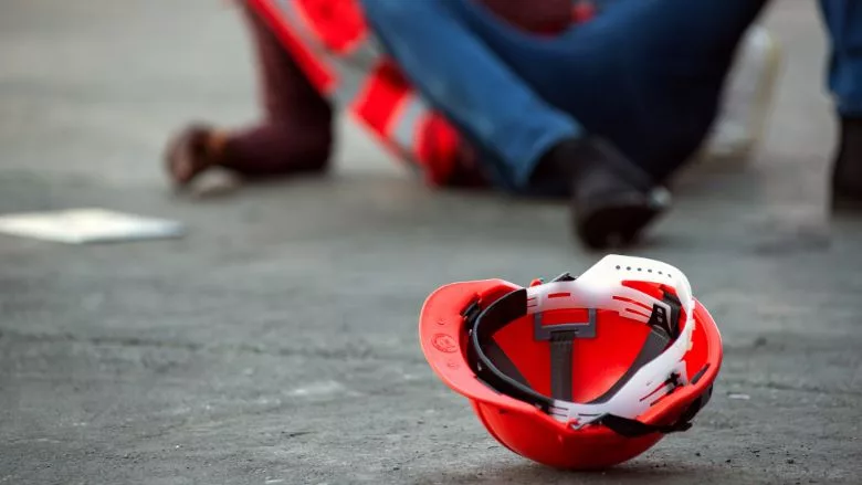 injured worker on the ground with hard hat in the foreground