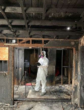 restoration technician documenting damage after a house fire