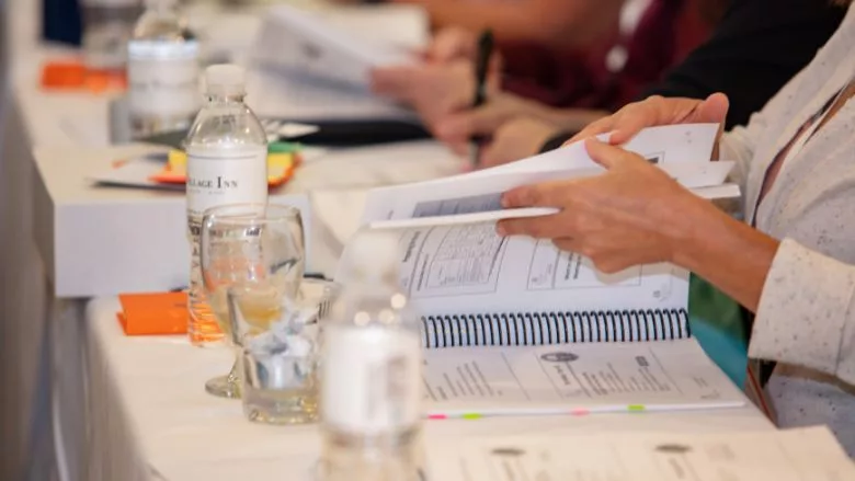 Training notebook on table with people reviewing the contents