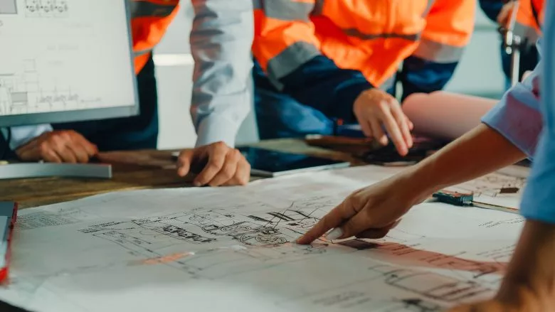 team of engineers analyzes blueprints