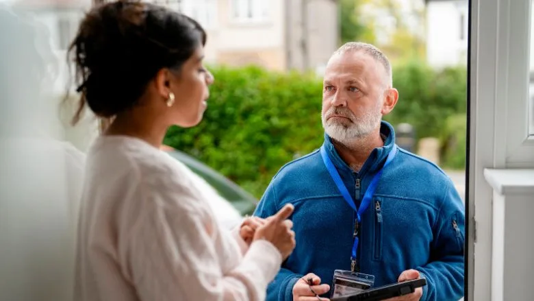 salesman discussing home services with a woman at her door