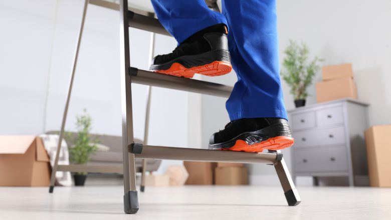 Professional worker climbing up ladder in room, closeup