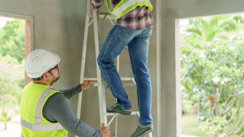 contractor on ladder while another holds the base