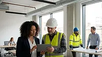 Contractor and female executive on jobsite conversing 