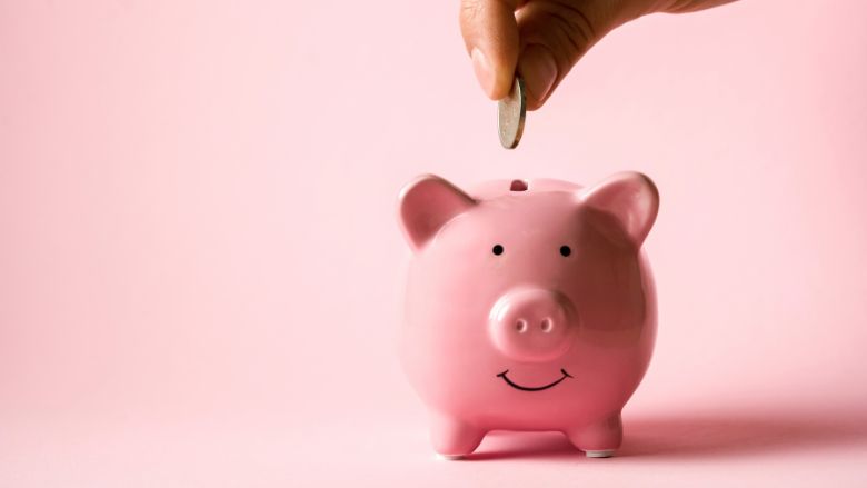 Hand puts a coin in a piggy bank