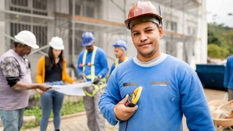 Construction electrician standing on a building site with people working in the background